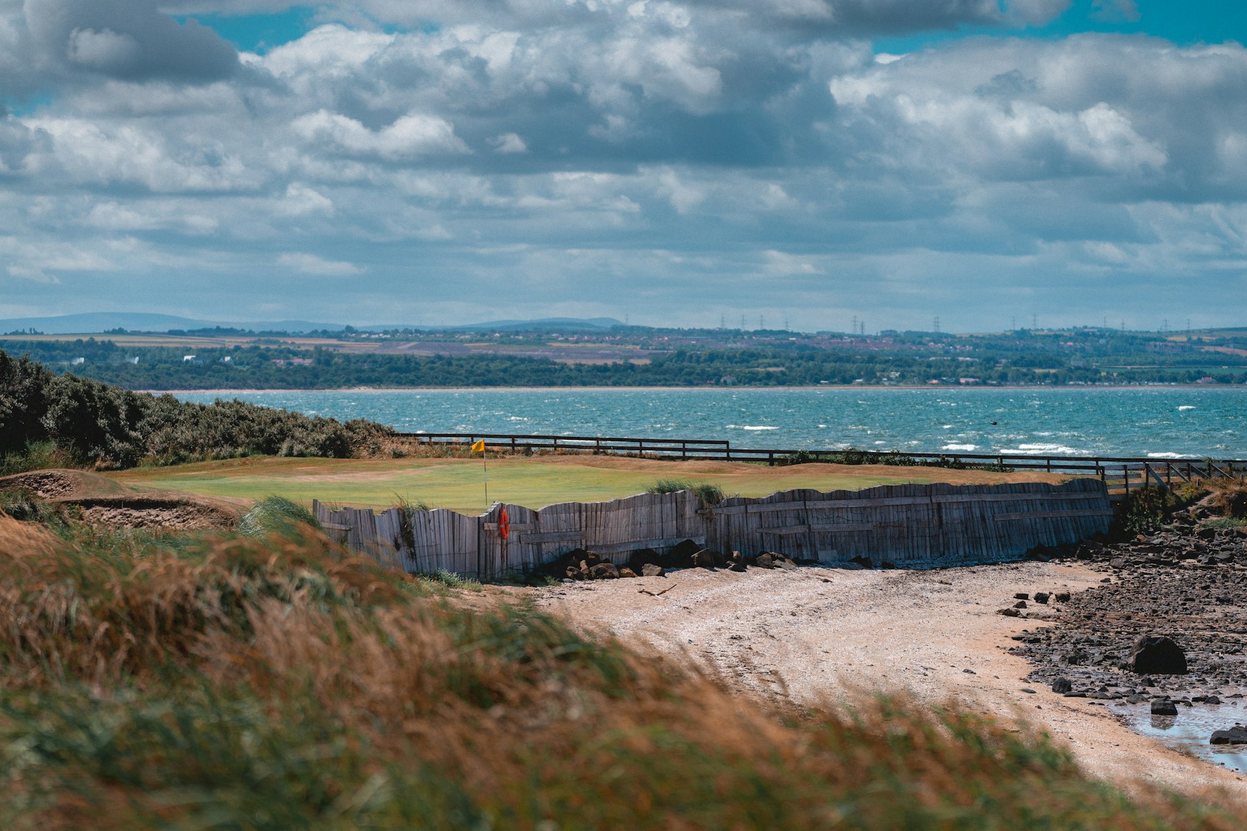 Placeholder image: a links-course green above a driftwood beach on a cold northern sea