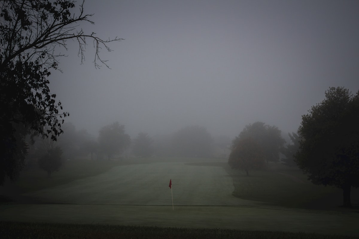 Placeholder image: a red flag on a fairway in heavy morning fog
